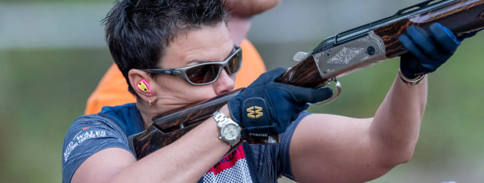 a woman taking part in shooting, wearing custom moulded ear plugs.